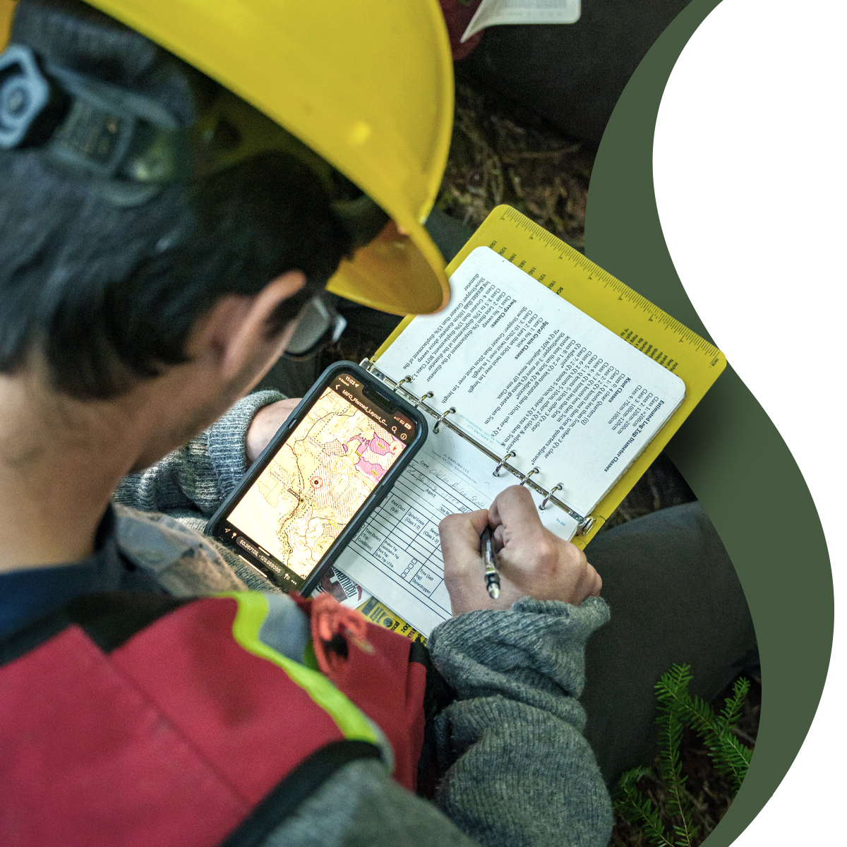 A worker reviews maps and notes in the field.